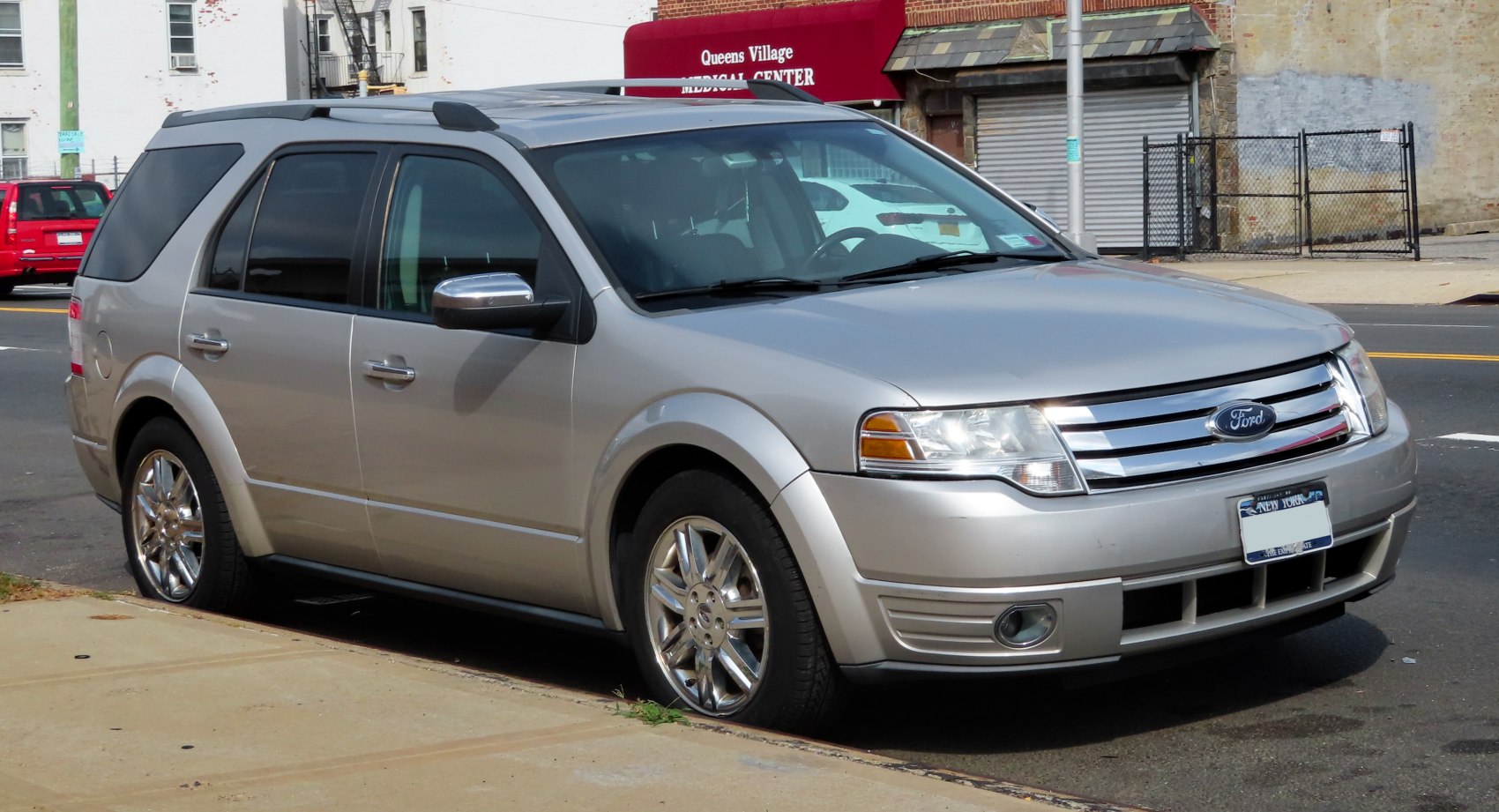 Front-side view of a silver mid-size SUV with chrome wheels and roof rails