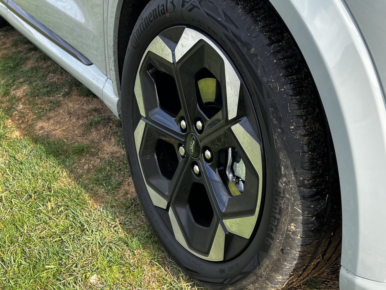 Close-up of alloy wheel with Continental tire on light-colored vehicle fender