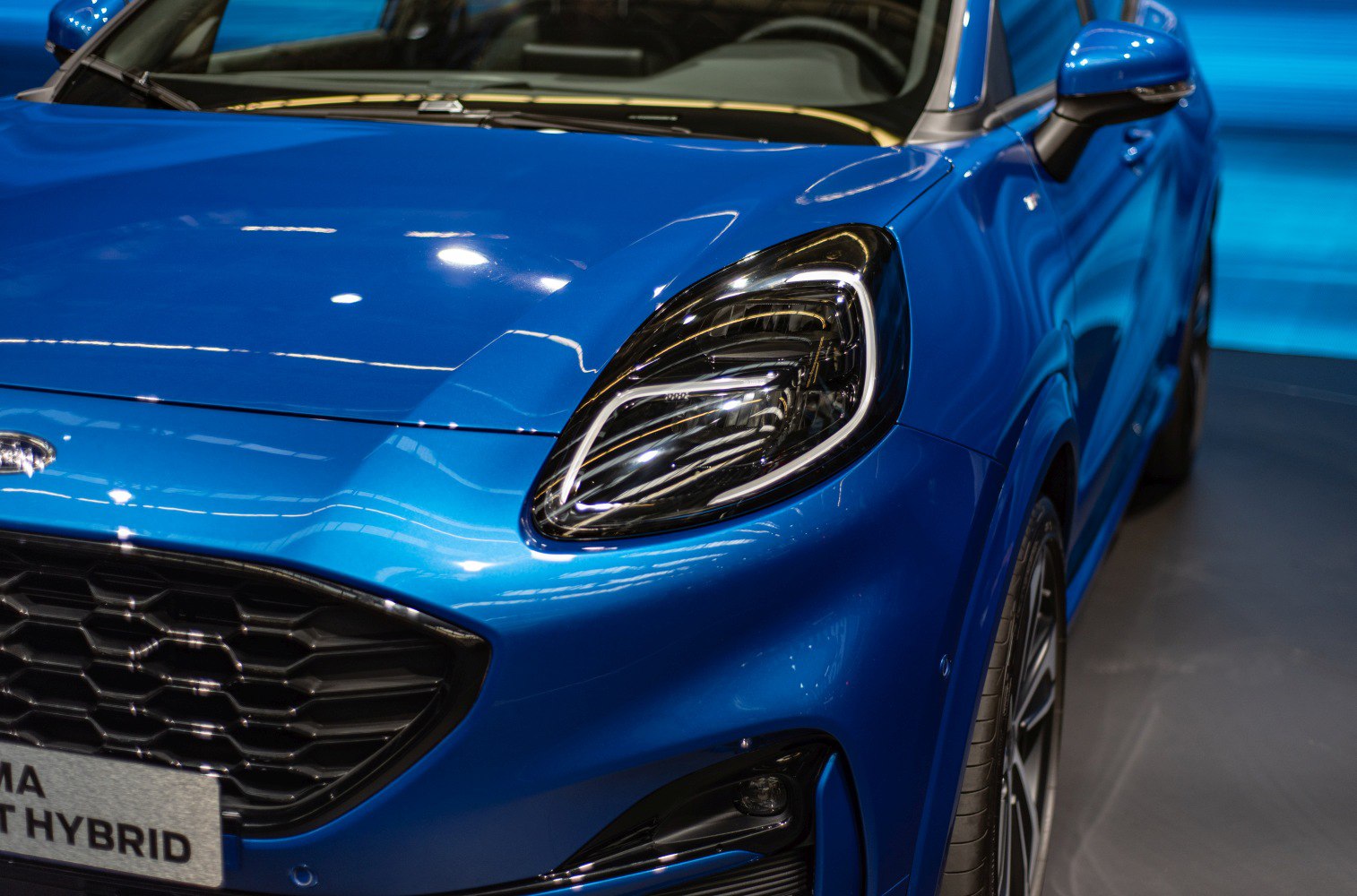 Close-up of sleek LED headlight and honeycomb grille on front side.