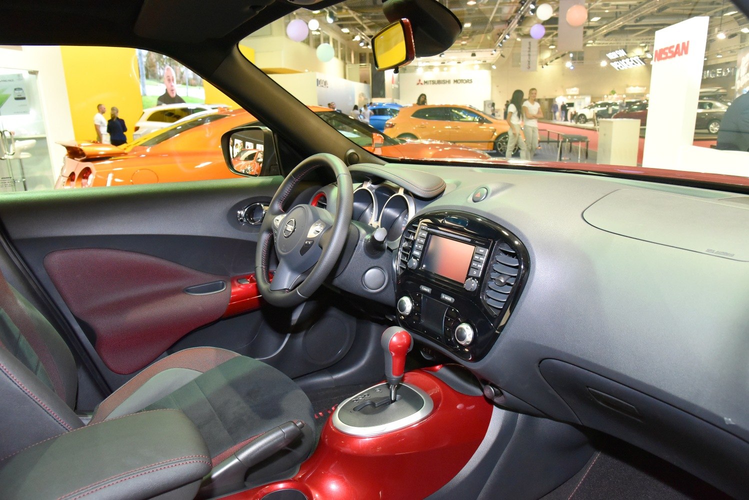 Sporty car interior with red accents on gear lever and door panels.