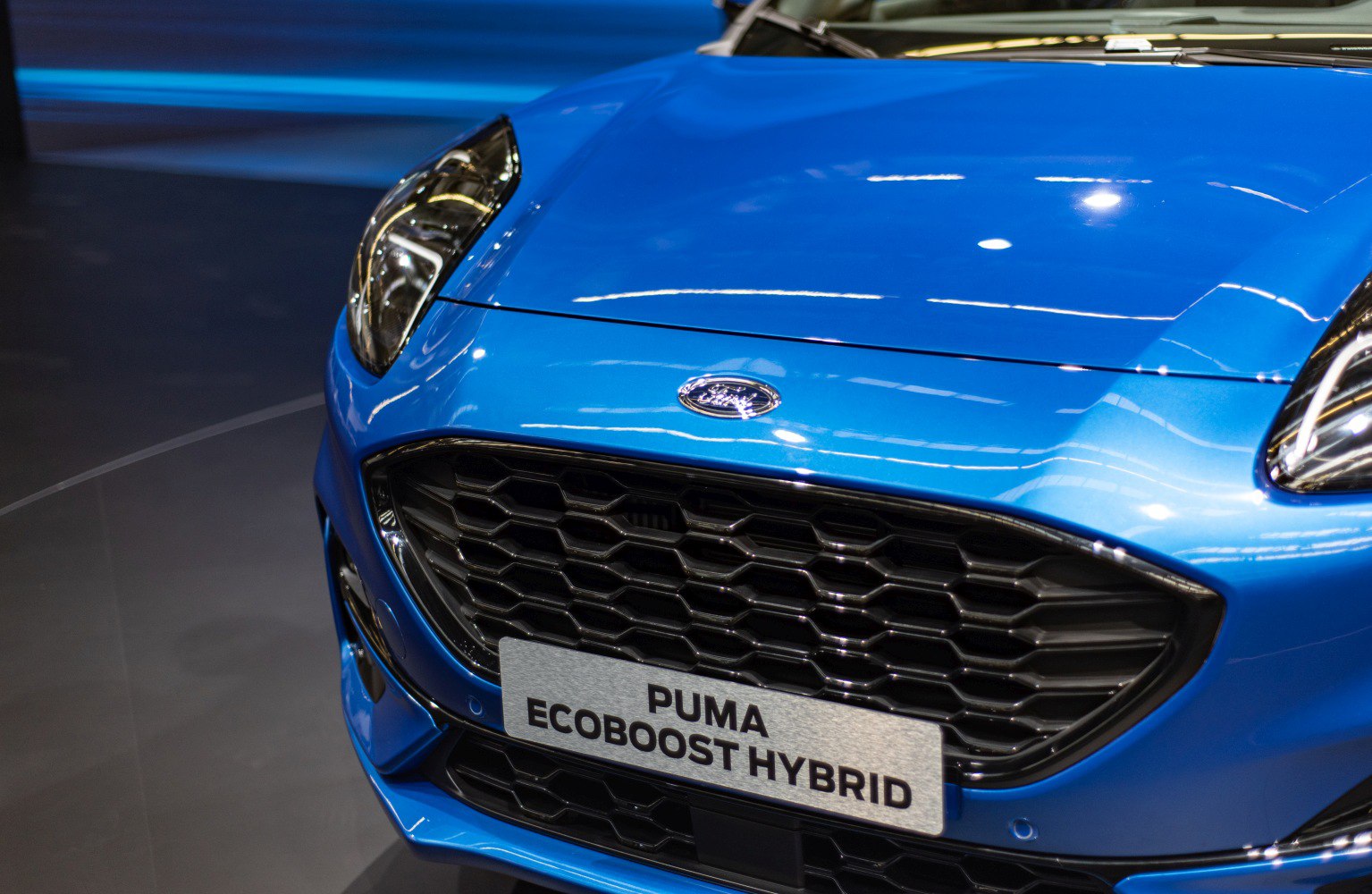 Close-up of front grille and distinctive headlight on blue car