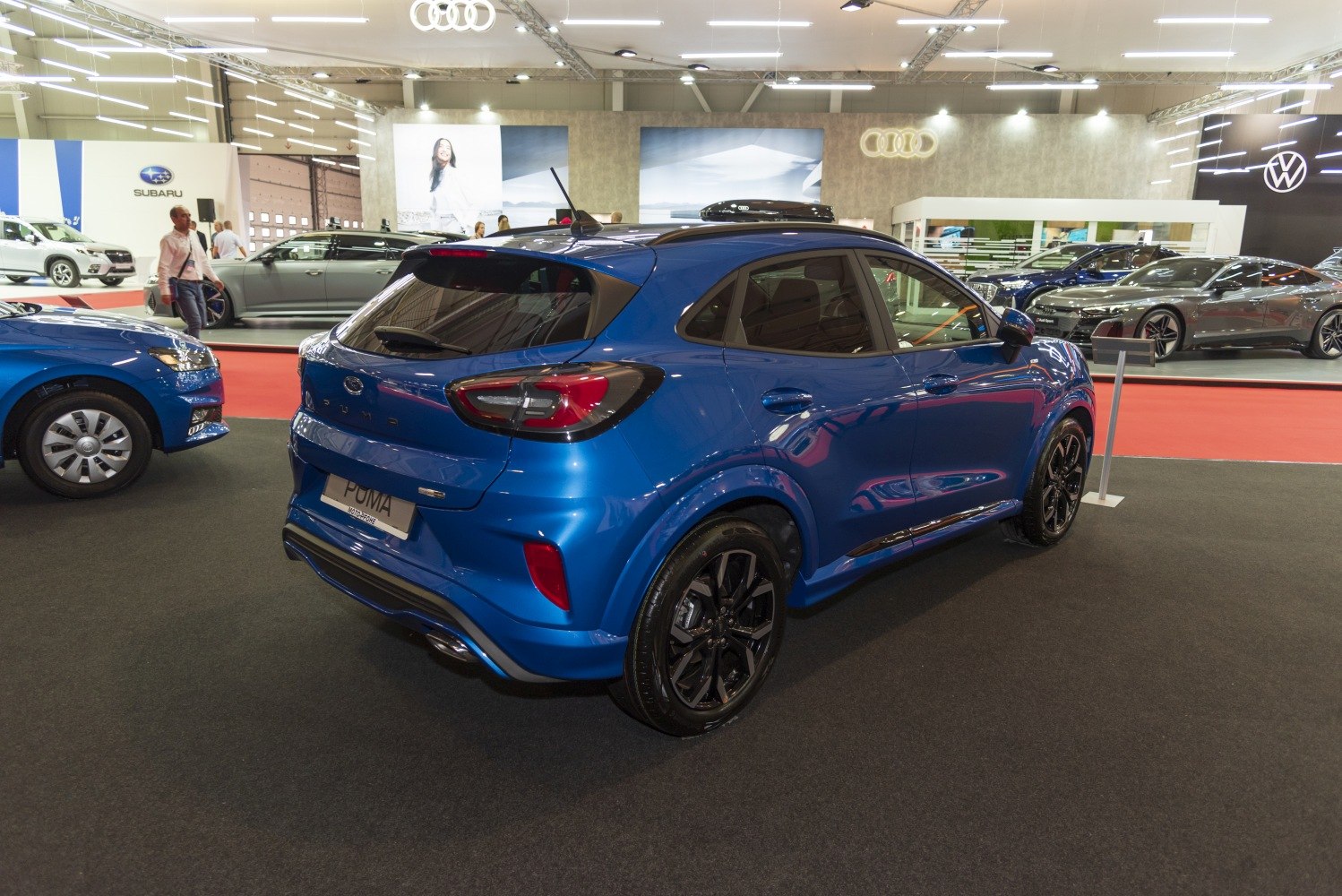 Rear three-quarter view of a blue compact sporty SUV with black wheels