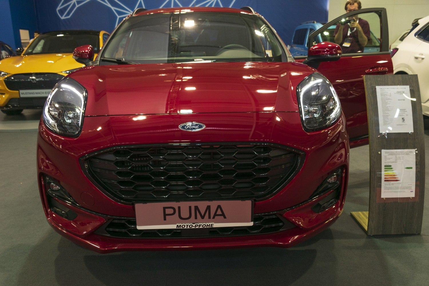 Honeycomb grille and distinctive headlights of a red compact SUV front.
