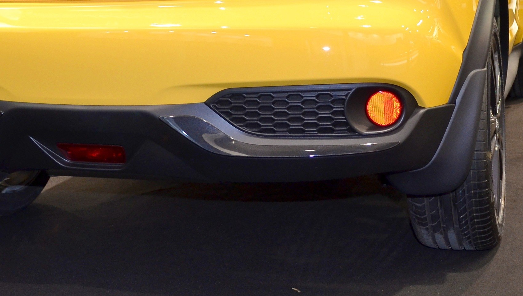 Close-up of rear bumper with hexagonal grille and round reflector