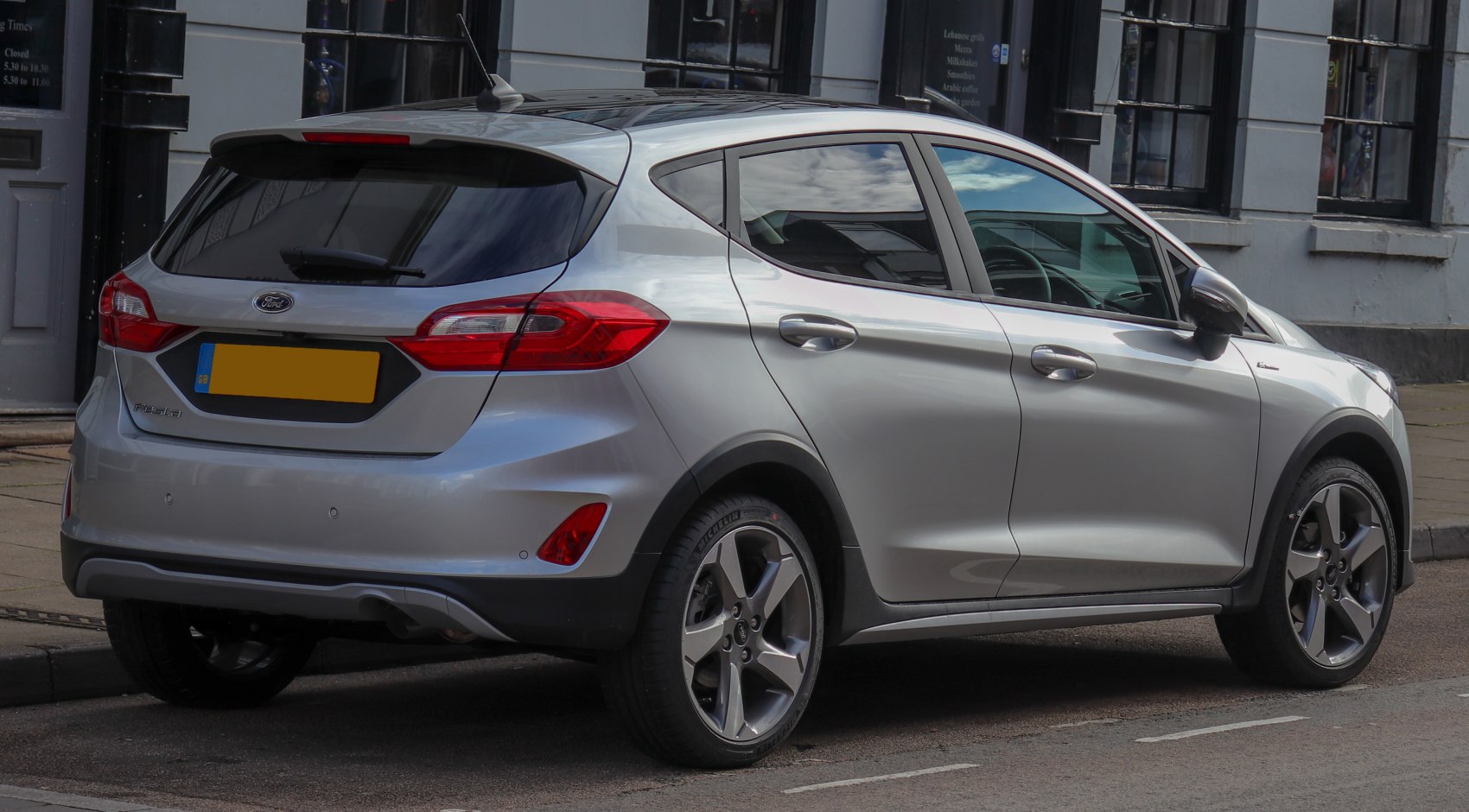 Silver hatchback rear side with alloy wheels and rear roof spoiler