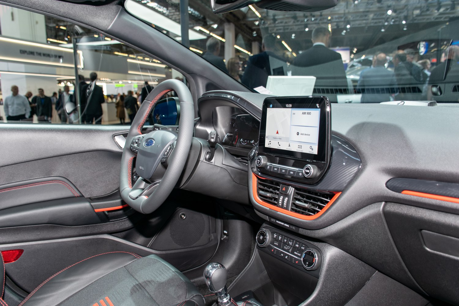 Touchscreen infotainment system and multifunction steering wheel with red stitching.