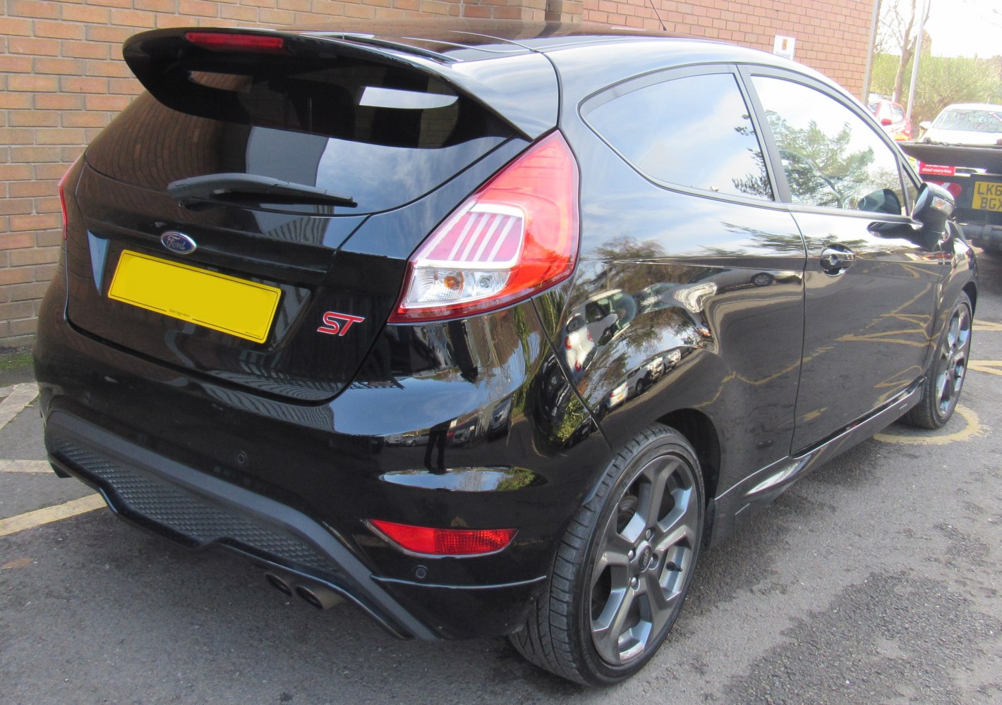 Rear view with spoiler, tail lights, dual exhaust, and five doors