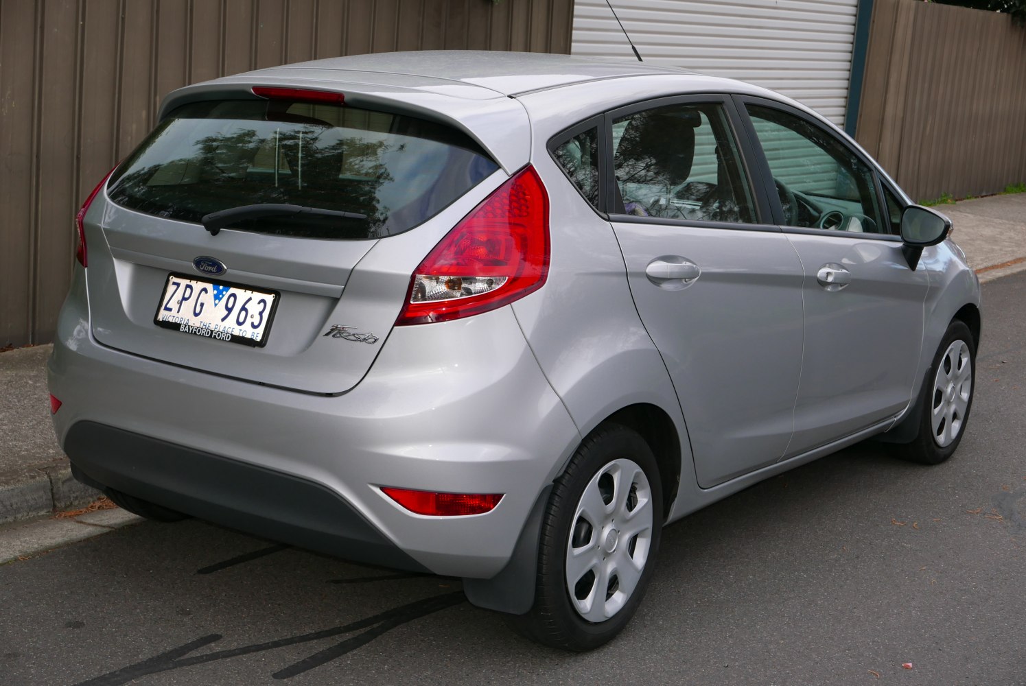 Rear view of silver 5-door hatchback with red tail lamps and rear windshield wiper