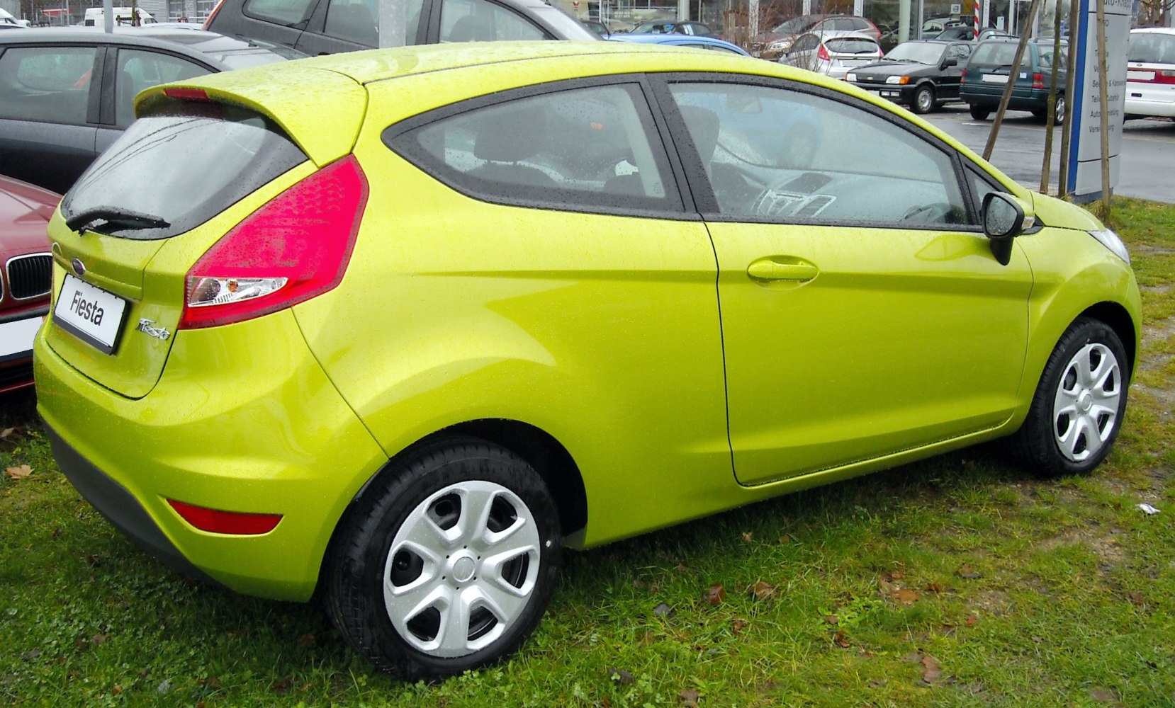 Rear side view of a lime green 3-door hatchback with smooth body lines.