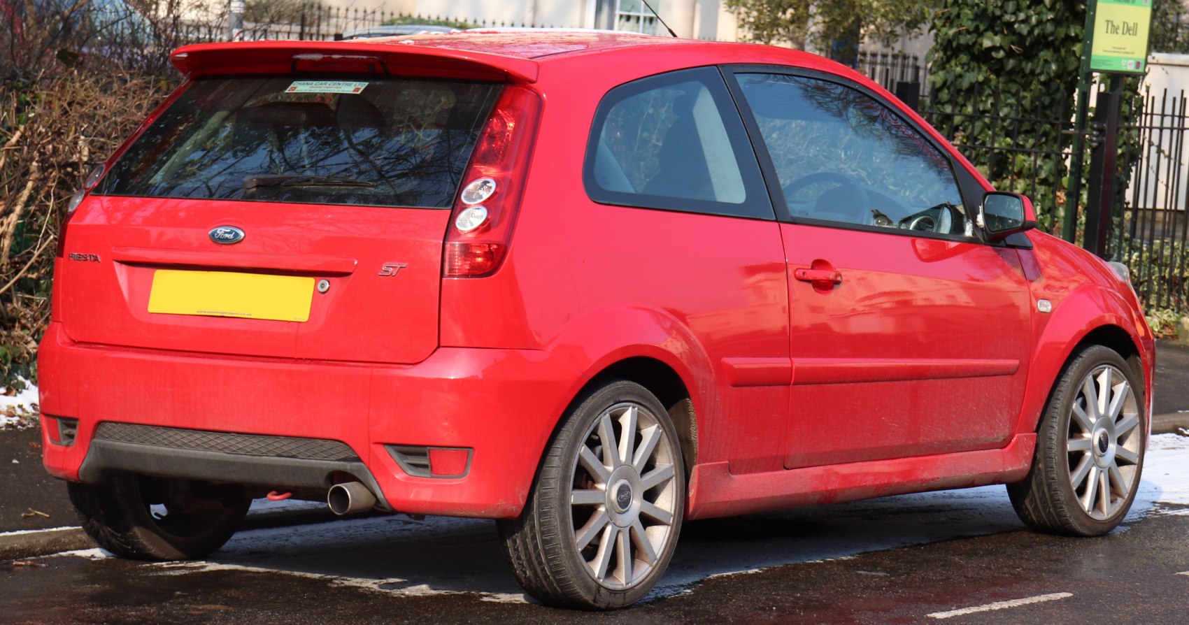 Rear and side view of red 3-door compact hatchback with alloy wheels and rear spoiler