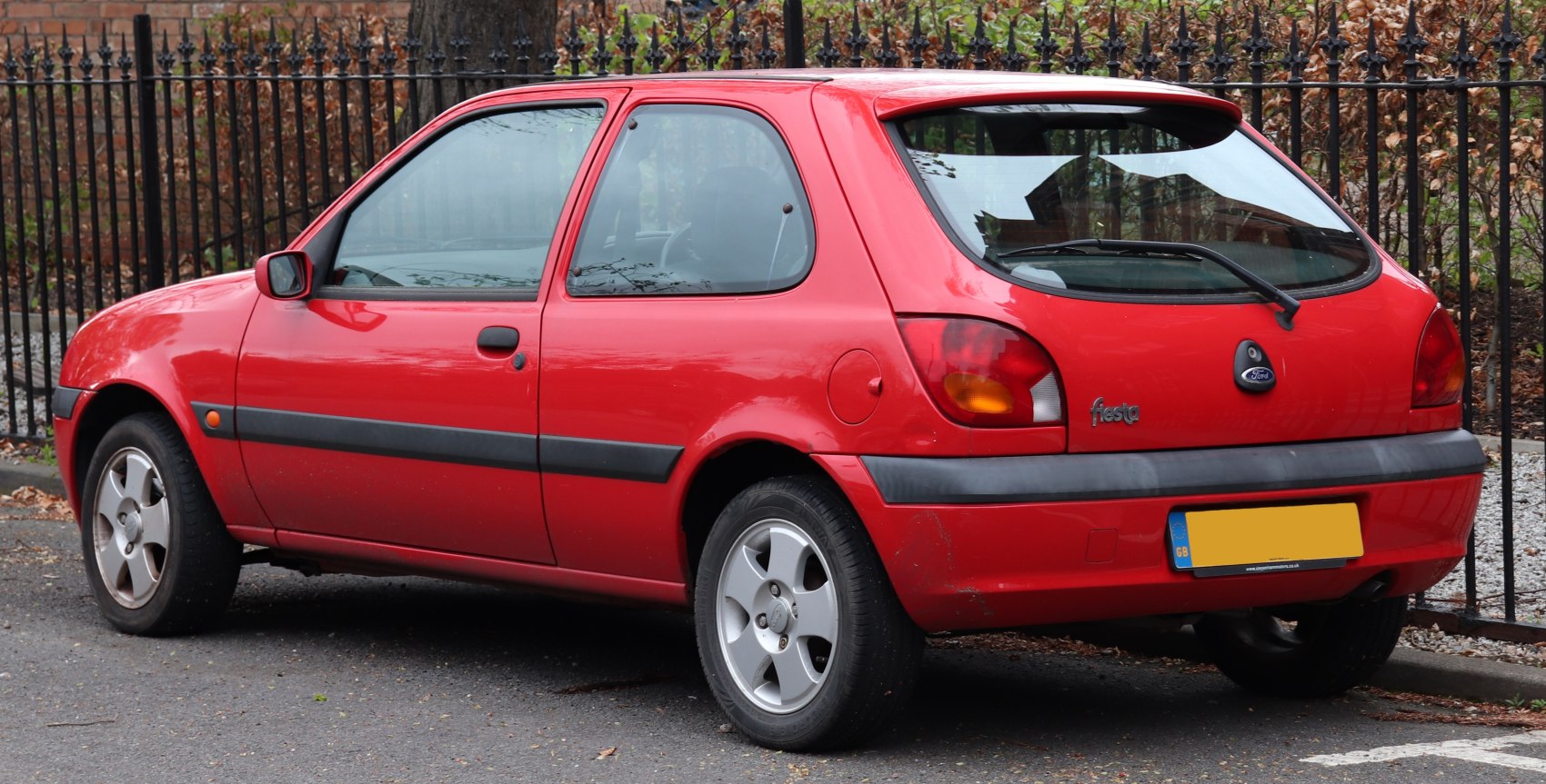 Red 3-door hatchback with black bumper and alloy wheels