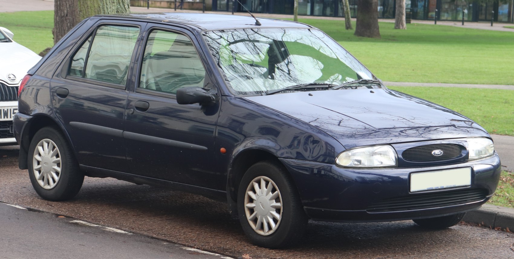 Front-side view of 5 door hatchback with rounded headlights and classic 90s compact design