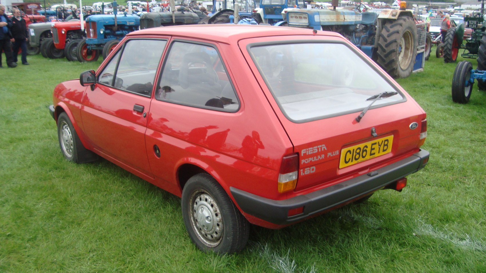 Red compact hatchback with rear side view, tail lights, and rear window wiper