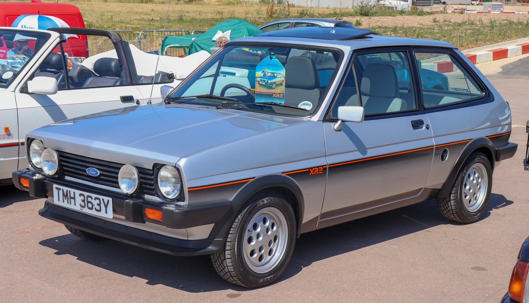 Silver retro hatchback with dual round headlights and sporty side stripe.