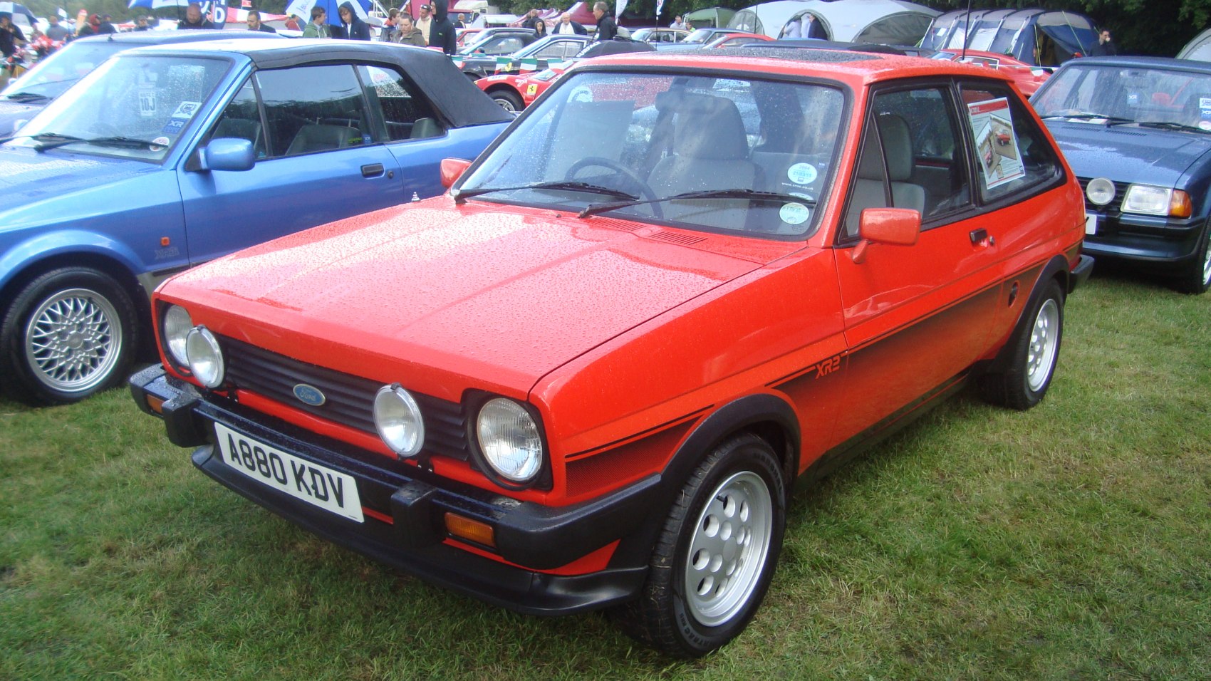 Red hatchback with dual front fog lights and alloy wheels on grass