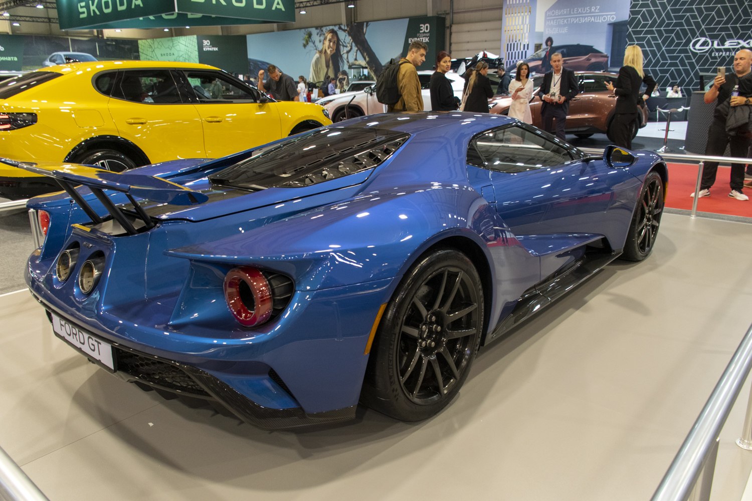 Sleek blue sports car rear with large spoiler and dual exhaust