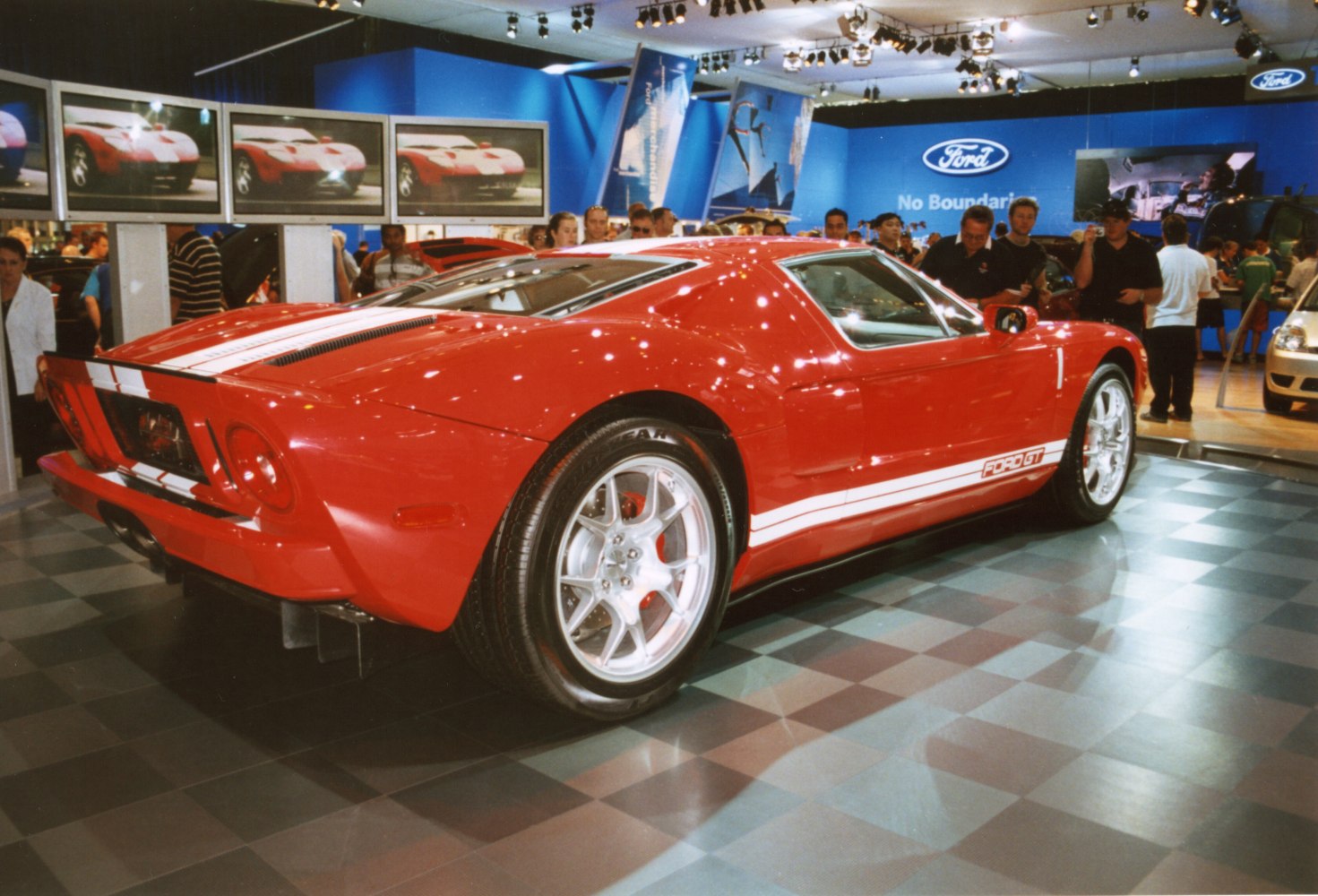 Red mid-engine sports coupe with white racing stripes and alloy wheels