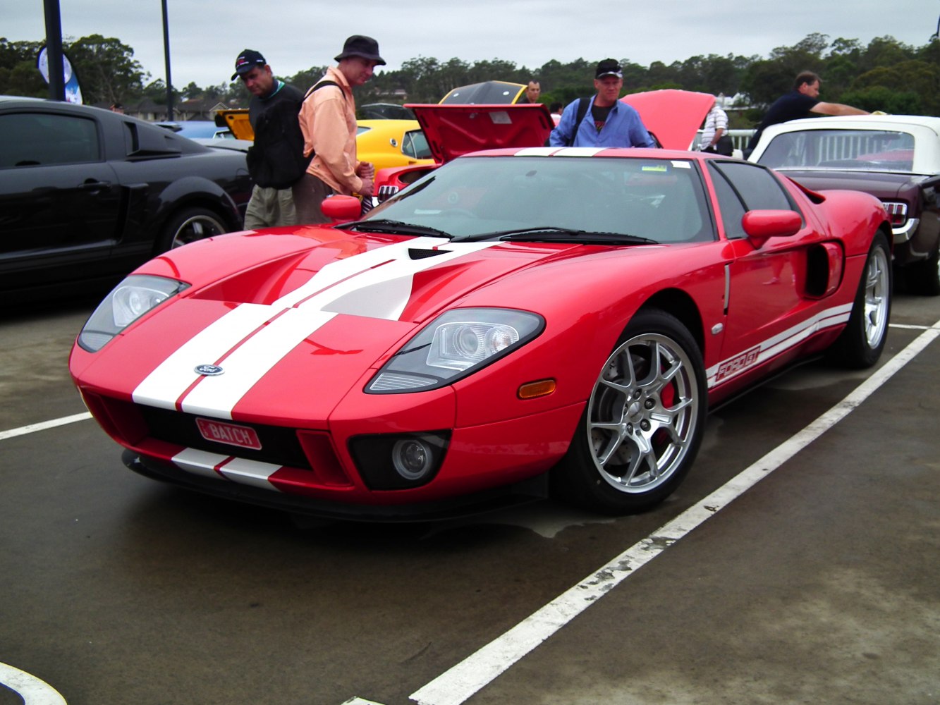 Red sports car with white racing stripes and aerodynamic body design