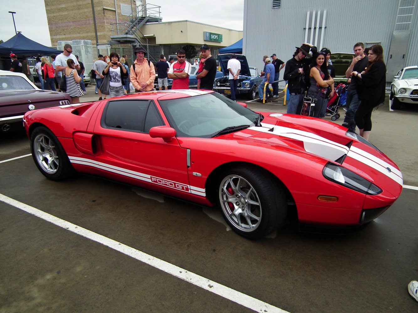 Red sports car with white racing stripes and silver alloy wheels
