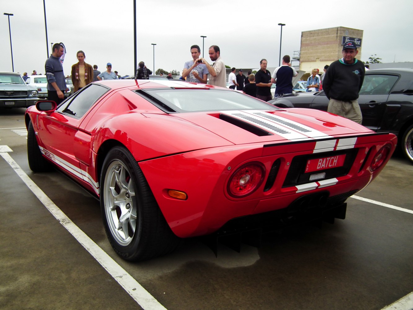 Rear view of red coupe with white racing stripes and round taillights