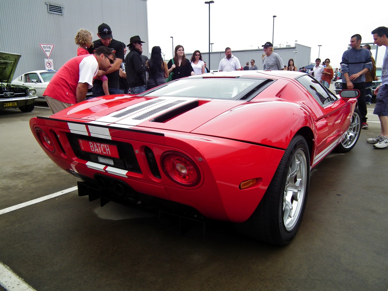 Rear view of red sports coupe with white racing stripes and distinct taillights.