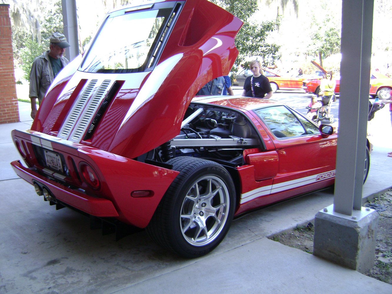 Rear hatch open with visible mid-engine and rear wheel of a red sports supercar