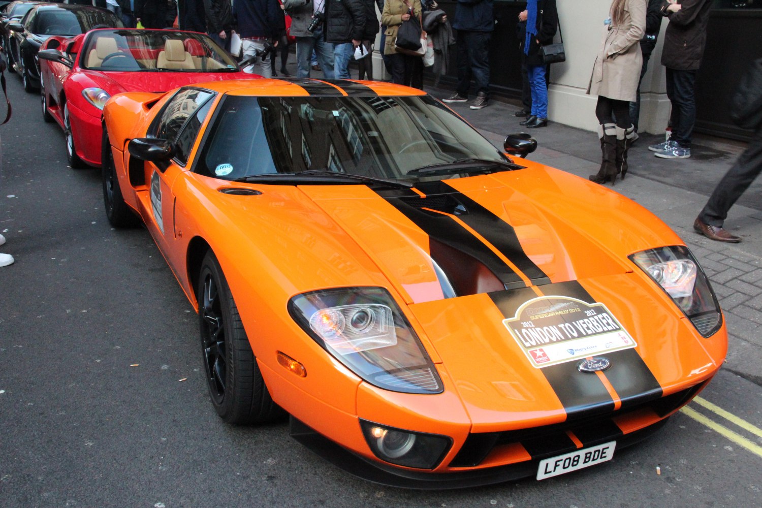 Orange mid-engine sportscar with black racing stripes