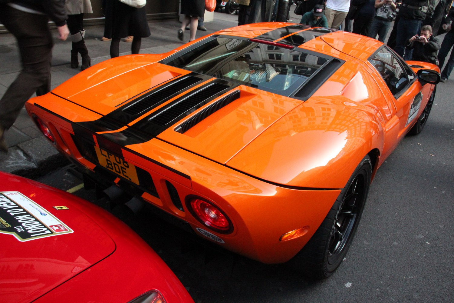 Sleek rear design with orange body, black accents, rear lights, and air vents