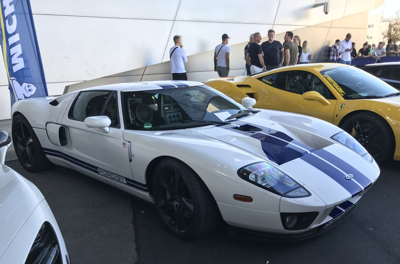 White sports car with blue racing stripes and mid-engine design