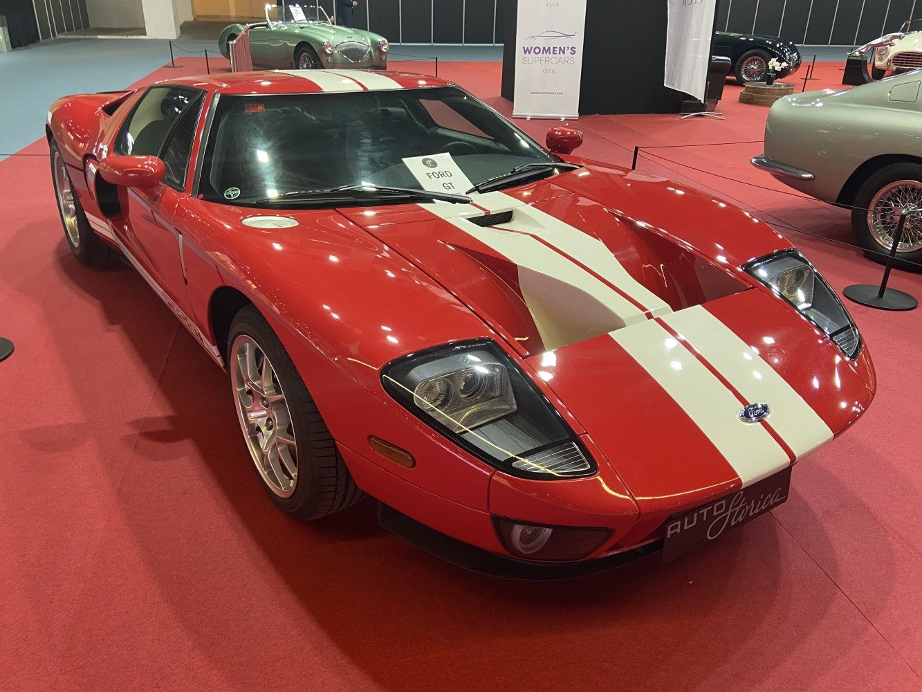 Red sports car front angled view with white racing stripes and sharp headlights