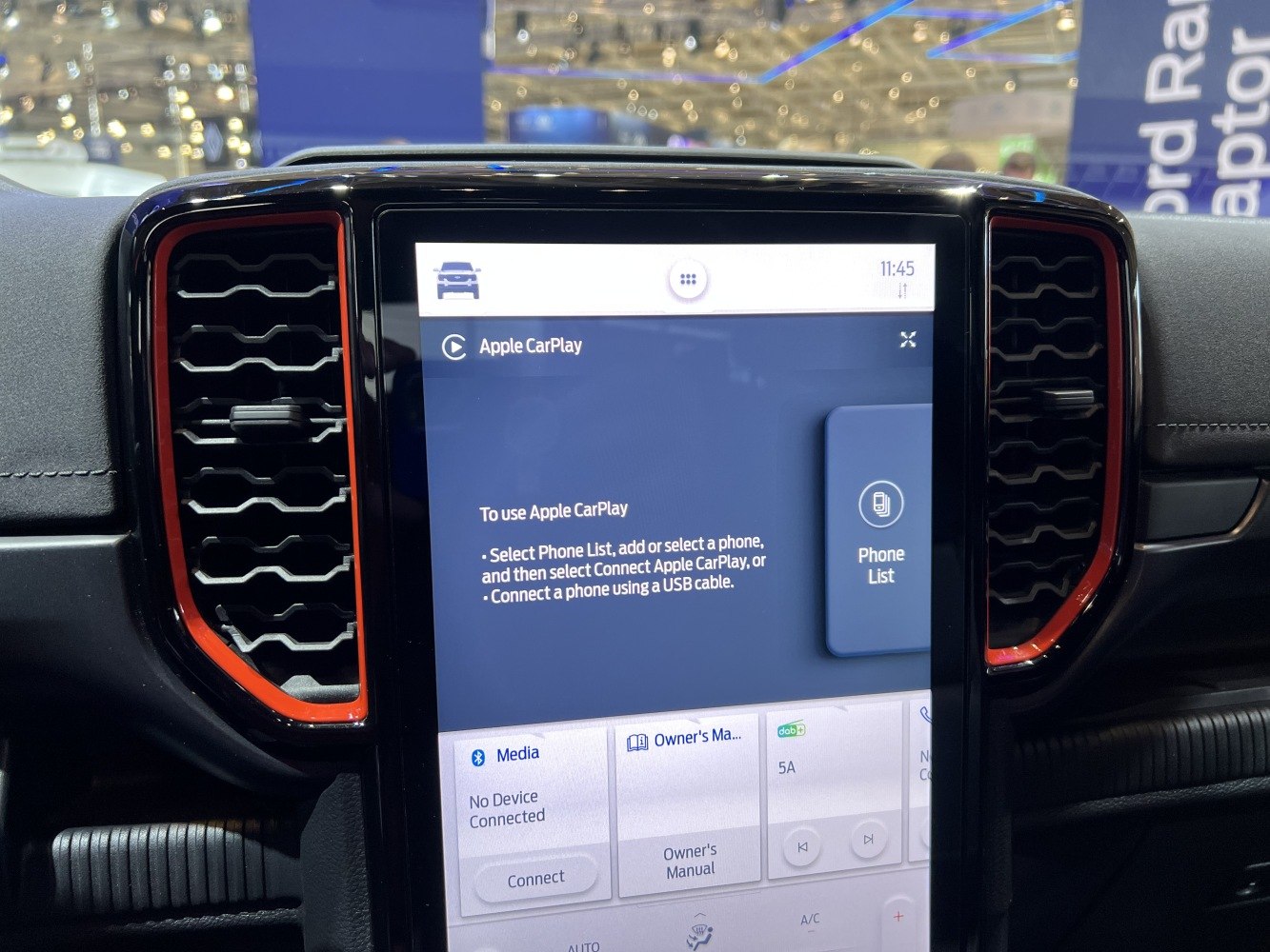Infotainment screen displaying Apple CarPlay with air vents framed by red trim