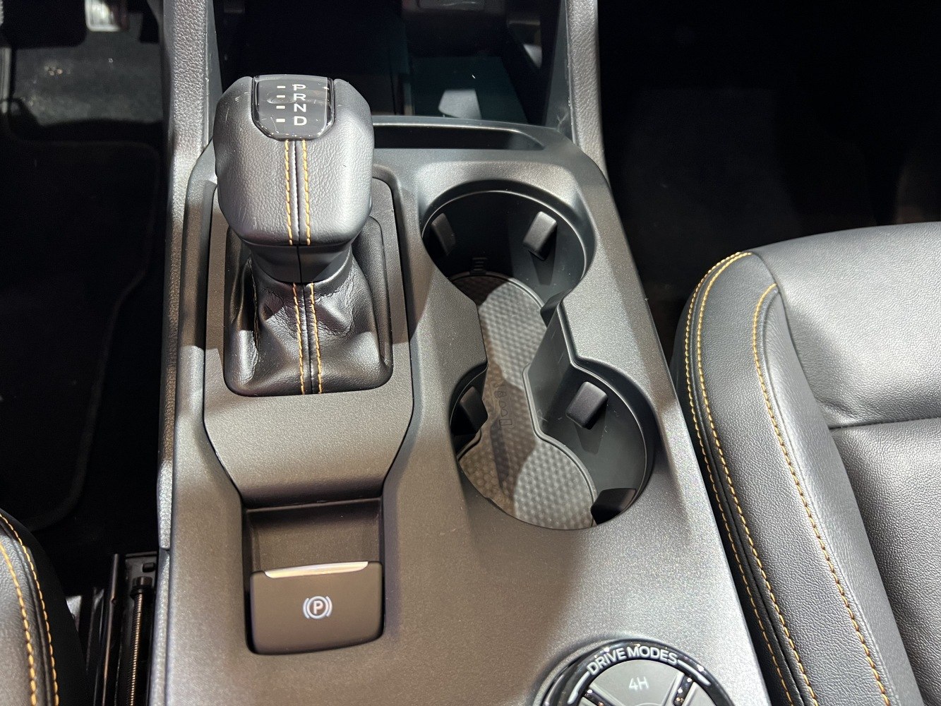 Automatic gear shift lever with cup holders and drive mode knob in console.