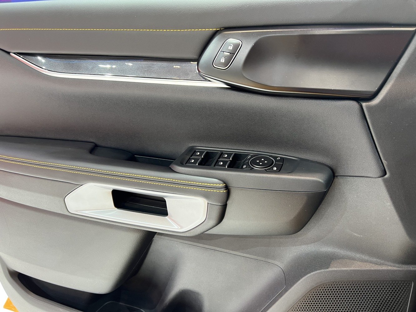 Interior door panel with control buttons and yellow stitching
