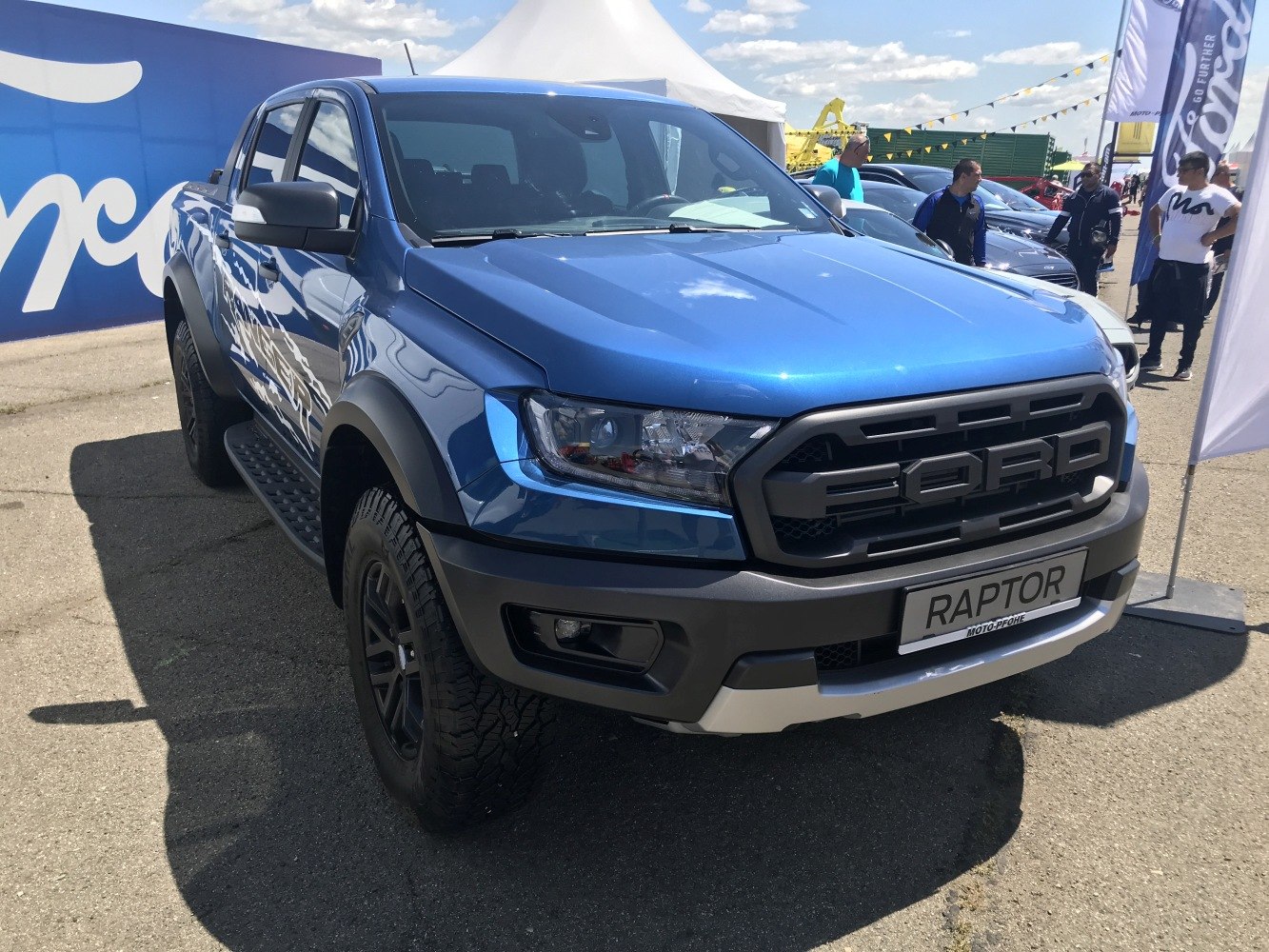Front view of blue pickup with aggressive grille and off-road tires