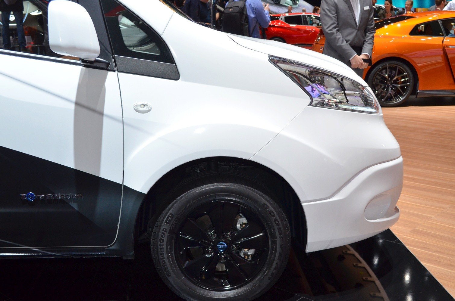 Close-up of electric van's front side with headlight, black wheel, and Zero Emission badge.