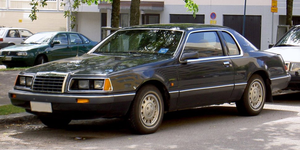 Front-side view of a classic 1980s coupe with rectangular grill and vintage wheels.