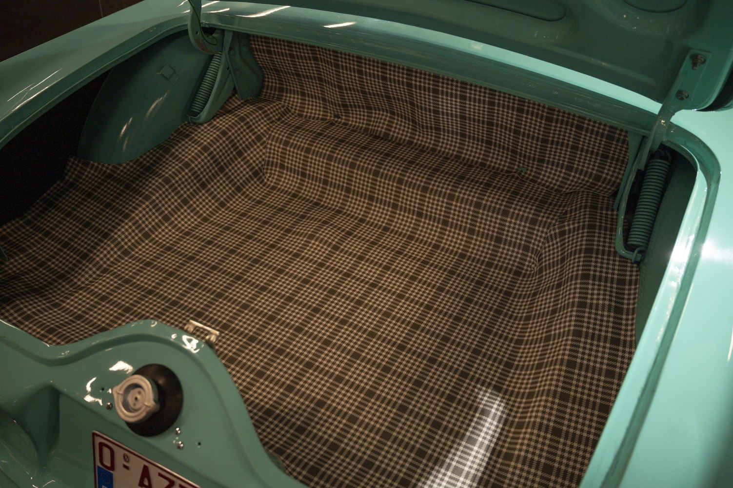 Plaid-lined trunk interior with spring-supported lid hinges