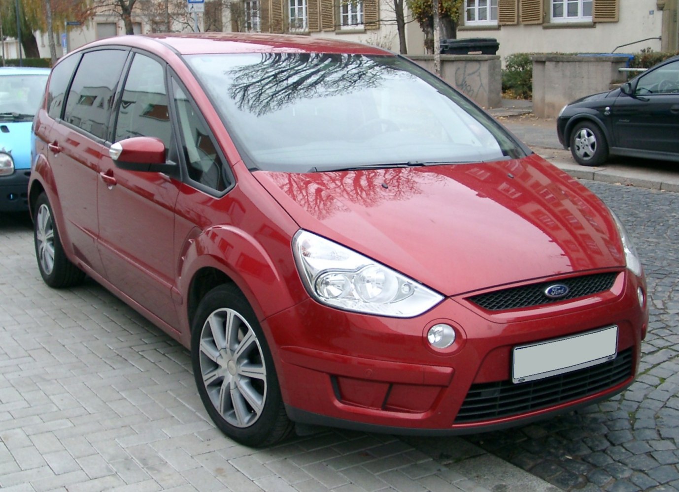 Red vehicle front-side with distinct headlights and alloy wheels