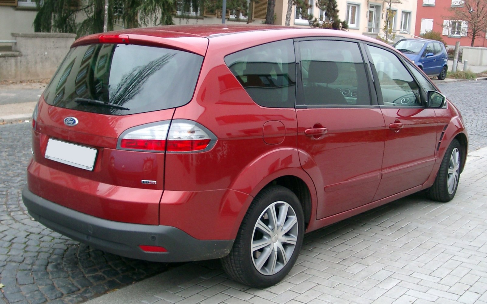 Rear profile of a red MPV with sleek tail lights and multiple windows