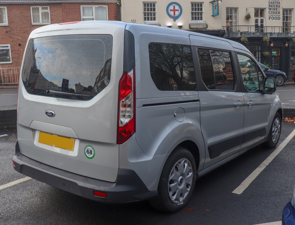 Rear side view of silver passenger van with tinted windows and vertical tail lights