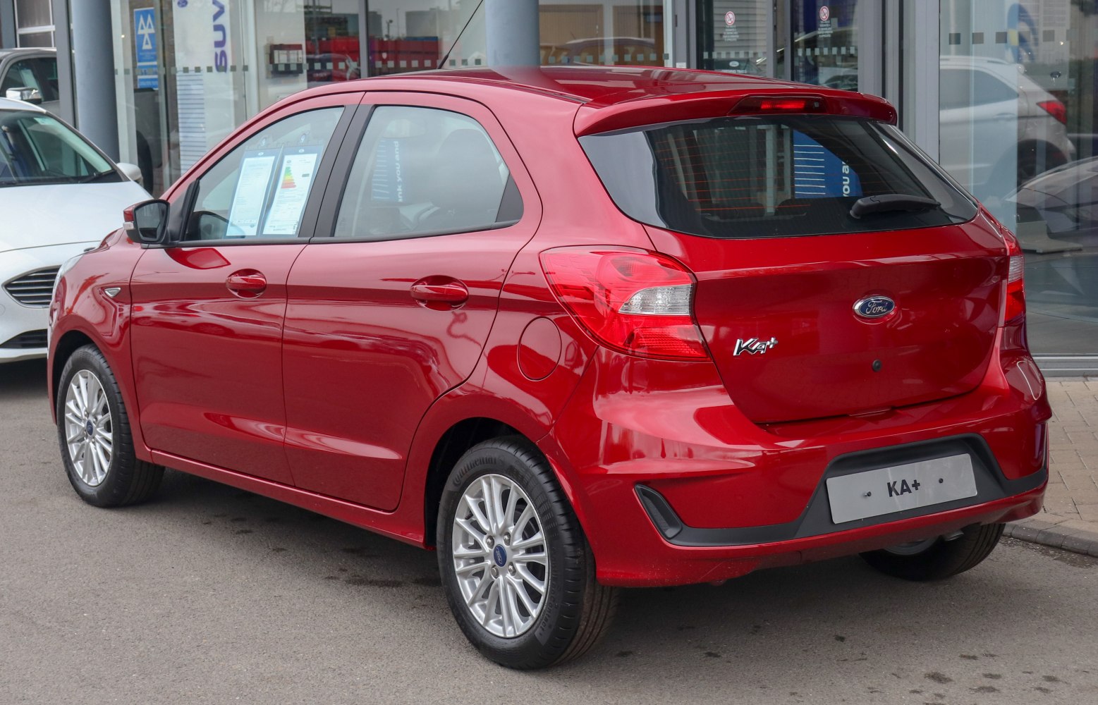 Red hatchback rear side profile with alloy wheels and tinted windows