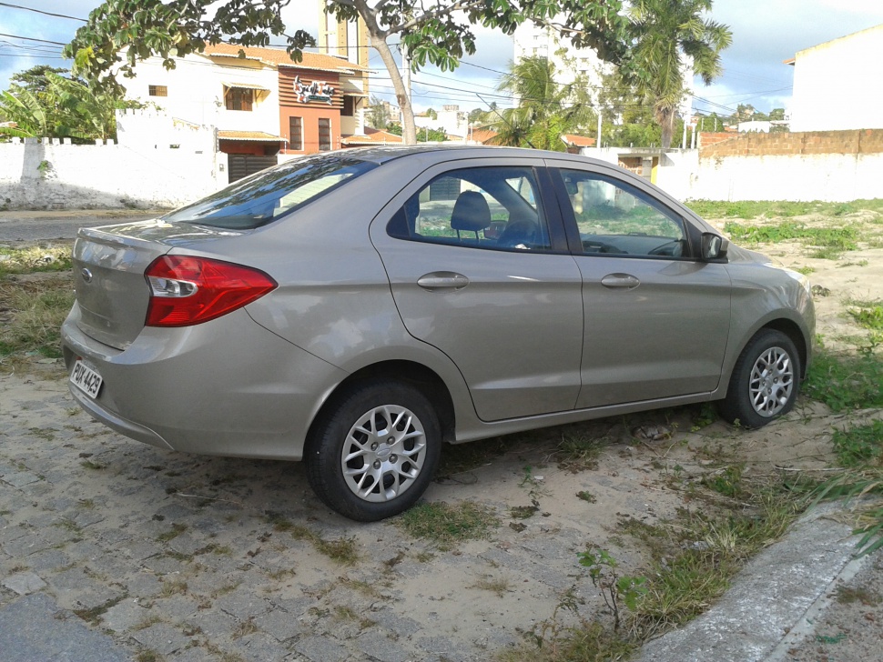 Silver subcompact sedan rear side with unique tail lights and alloy wheels.