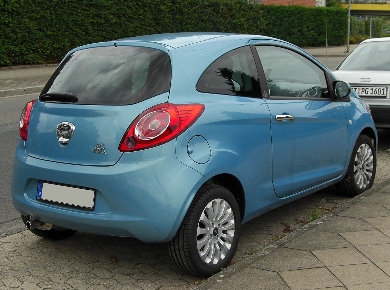 Rear view of a compact hatchback with round red taillights and blue body.