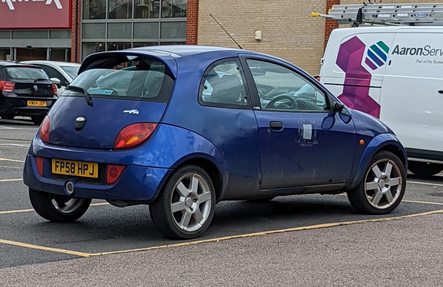 Blue hatchback with rear spoiler and alloy wheels parked in lot