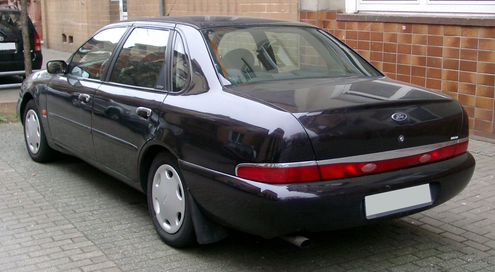 Rear view of a mid-90s sedan with distinctive long red taillight and sleek body lines