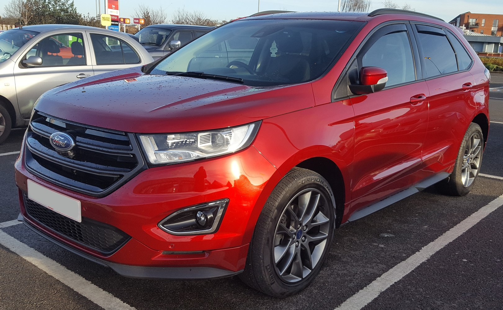 Red SUV front close-up with alloy wheels and black grille