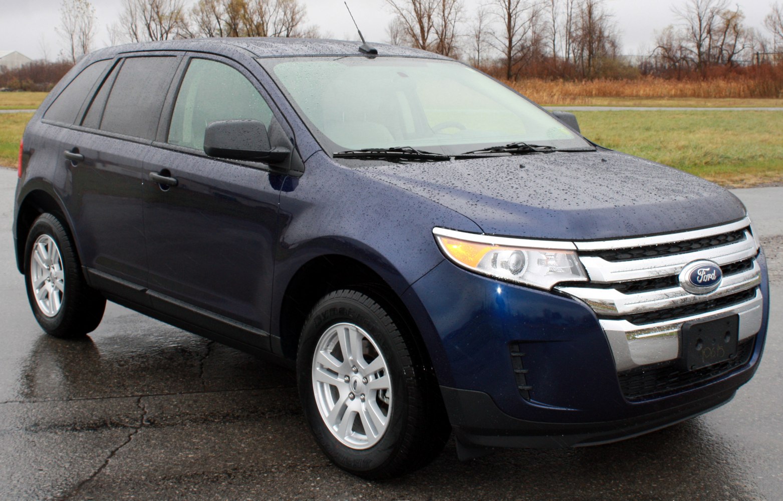Chrome grille and headlight detail on wet midsize SUV front.