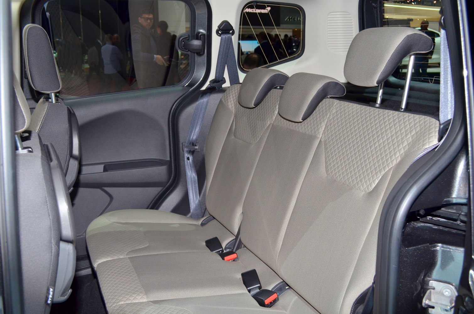 Rear passenger seats with fabric upholstery, headrests, and seatbelt setup