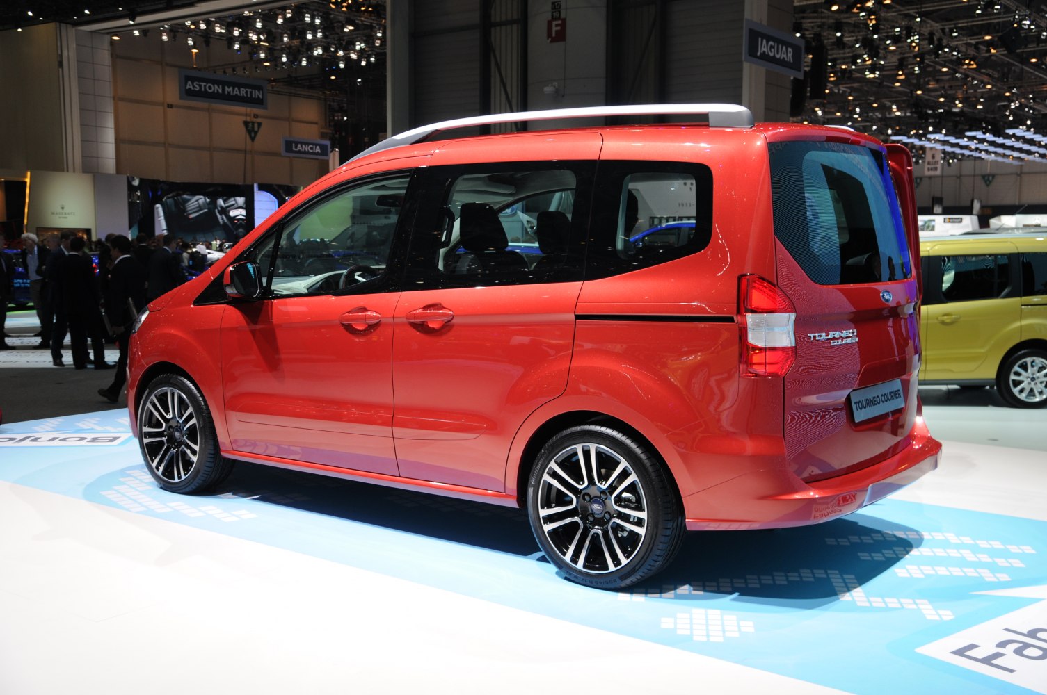 Side view of red compact MPV showing sliding doors and alloy wheels