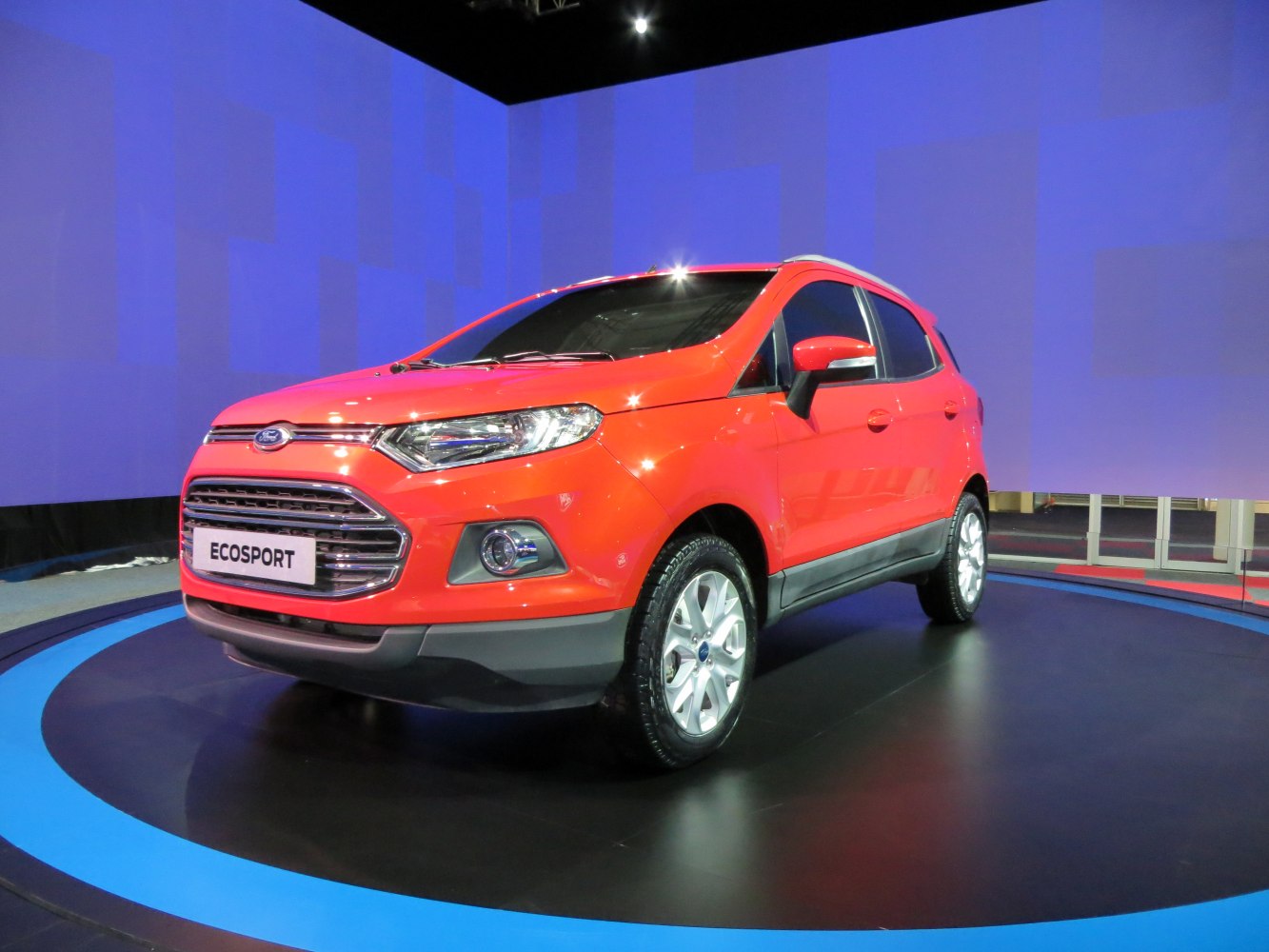 Front-side view of bright orange compact SUV with prominent grille and alloy wheels